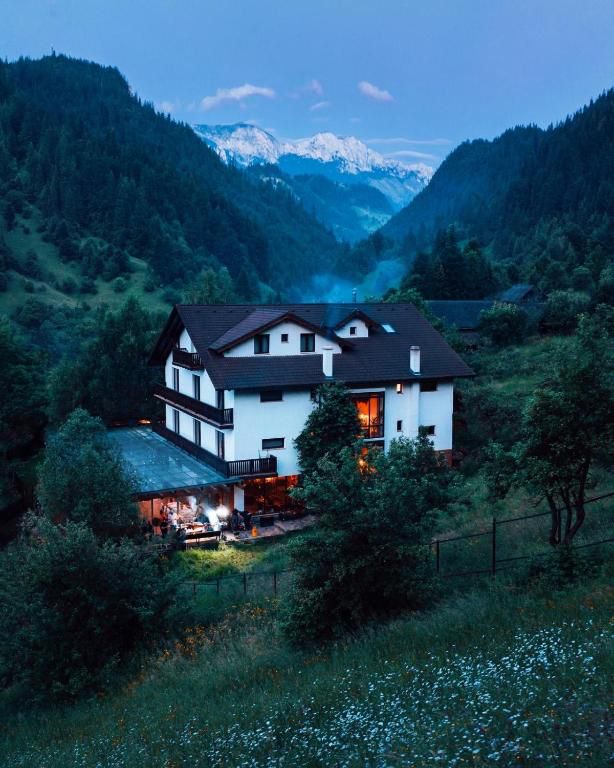 Casa văzută de pe deal în amurg, cu vârfuri înzăpezite în depărtare
